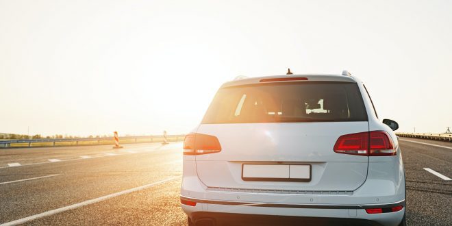 White crossover car on empty asphalt road at sunrise