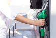 Woman pouring gasoline into her car at a gas station.