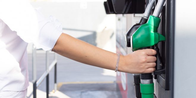 Woman pouring gasoline into her car at a gas station.