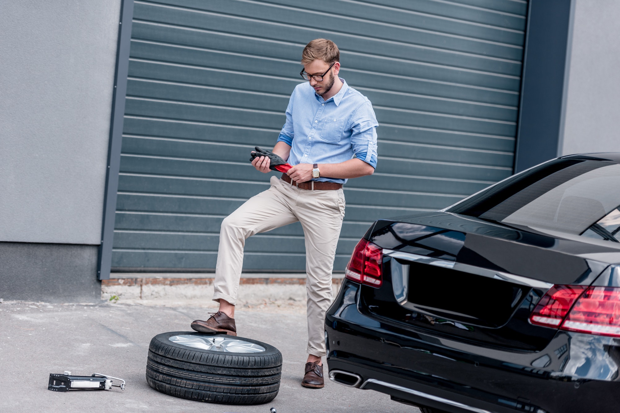young handsome man changing car tire