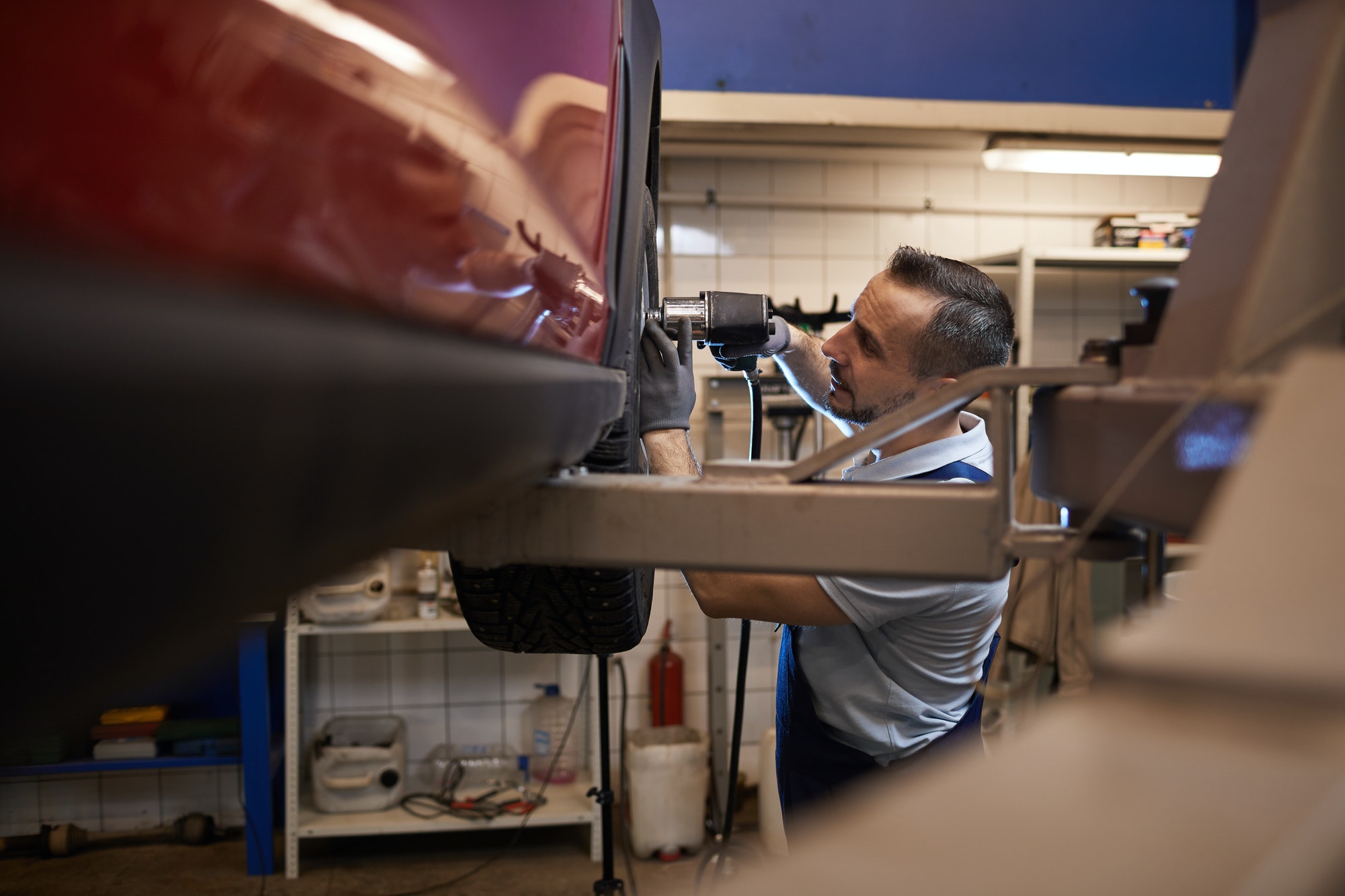 Mecánico cambia neumático a un coche rojo
