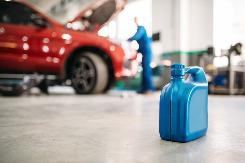 Una botella de aceite azul en el suelo de un taller mecanico