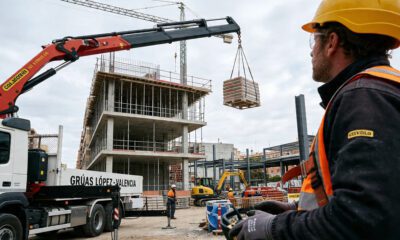 Camión pluma operando en una obra urbana en España, elevando materiales con precisión mediante brazo telescópico y control remoto, ejemplo real de maquinaria en construcción