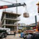 Camión pluma operando en una obra urbana en España, elevando materiales con precisión mediante brazo telescópico y control remoto, ejemplo real de maquinaria en construcción