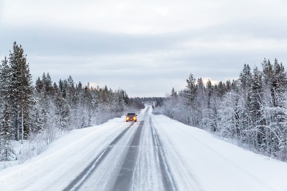 Un coche circula por una carretera nevada