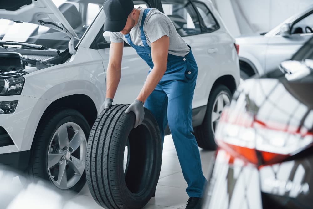 Mecanico mueve neumático entre dos coches