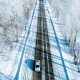 Aerial view of winter road with a car and snow covered trees.