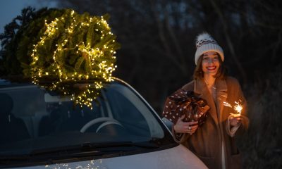 Woman with sprklers near car and Christmas tree outdoors