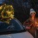Woman with sprklers near car and Christmas tree outdoors