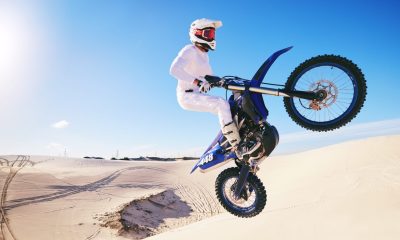 Jump, moto cross and man on motorcycle on sand for adrenaline, adventure and freedom in desert. Act
