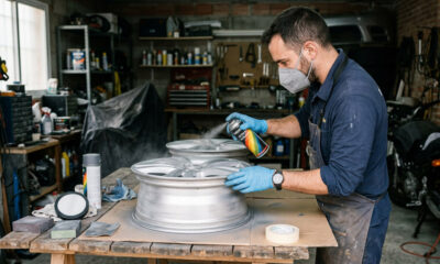 Un conductor restaura una llanta de aluminio desmontada utilizando pintura automotriz en aerosol para mejorar su aspecto y protección.