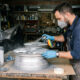 Un conductor restaura una llanta de aluminio desmontada utilizando pintura automotriz en aerosol para mejorar su aspecto y protección.