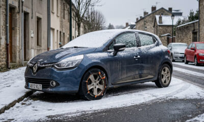 Coche aparcado con cadena textil instalada en la rueda sobre nieve ligera en entorno real.