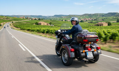 Un conductor viaja en un trike clásico tipo touring por una carretera secundaria rodeada de viñedos en La Rioja, mostrando la estabilidad y comodidad de este tipo de vehículo para trayectos largos.