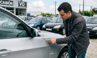 Comprador revisando la carrocería de un vehículo usado en busca de diferencias en paneles y alineación durante una inspección visual.